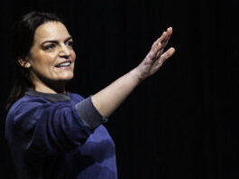 Writer & Actor Kim Kalish hold a hand out.