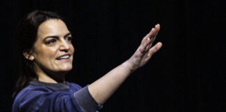 Writer & Actor Kim Kalish hold a hand out.
