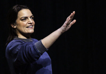 Writer & Actor Kim Kalish hold a hand out.